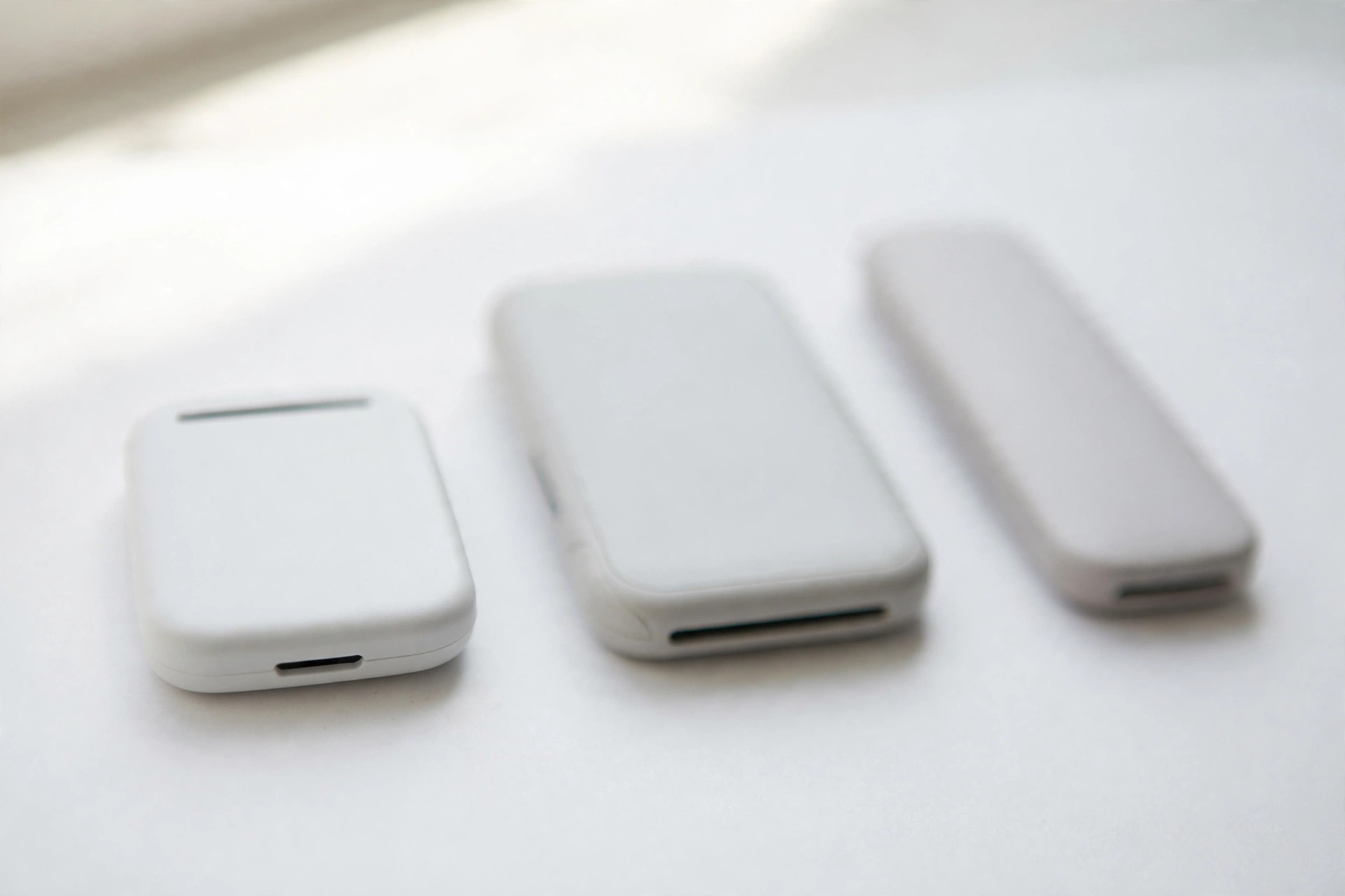 Three small white mobile card readers in a row on a white surface